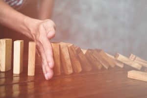 Frauenhand stoppt fallende Dominosteine als Symbol für den IT-Notfallplan